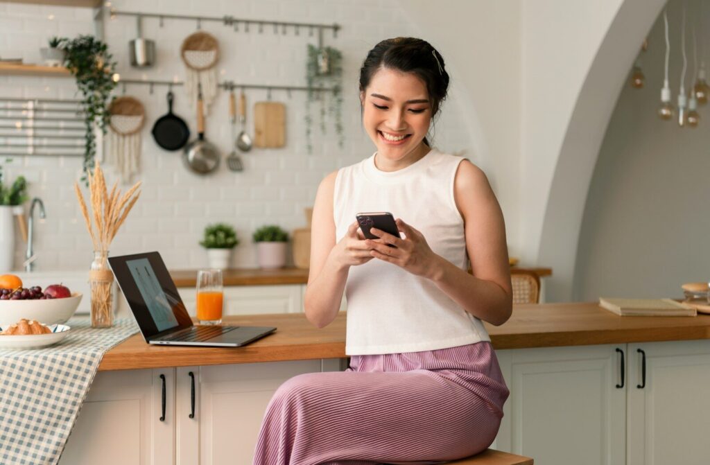 a woman sitting on a stool looking at a cell phone
